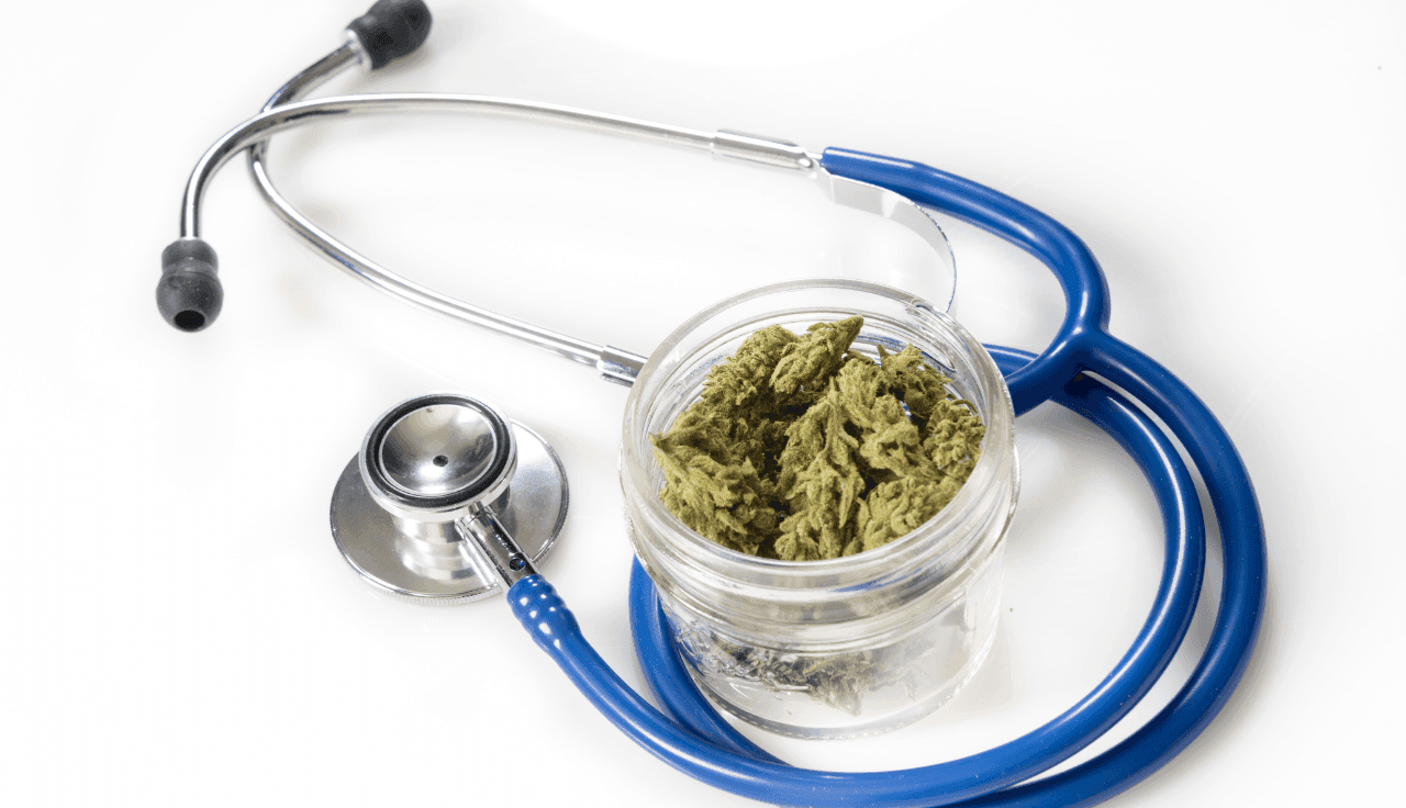 Glasbehälter mit medizinischem Cannabis neben einem Stethoskop