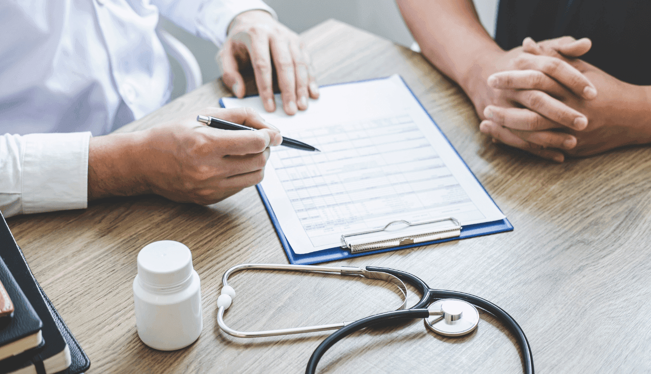 Arzt berät Patienten und notiert Informationen auf einem Formular.